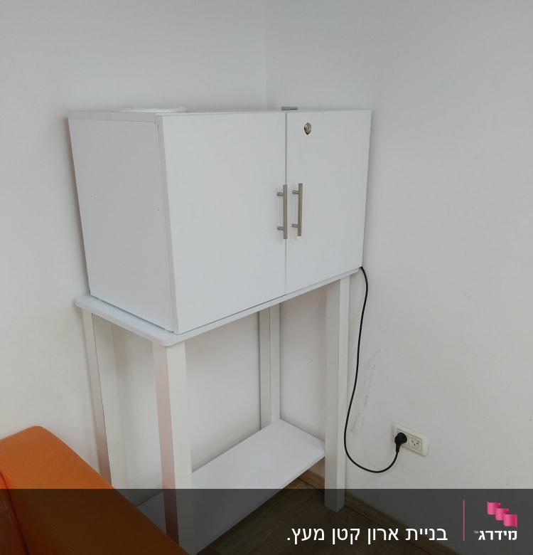 ארון לבן עם ידיות מתכת על שולחן